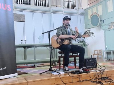 Emil Ernerbro sitter på en scen med en gitarr på en Clinic på Rytmus Borlänge.