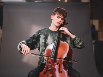 En elev blundar och spelar cello i en fotostudio.