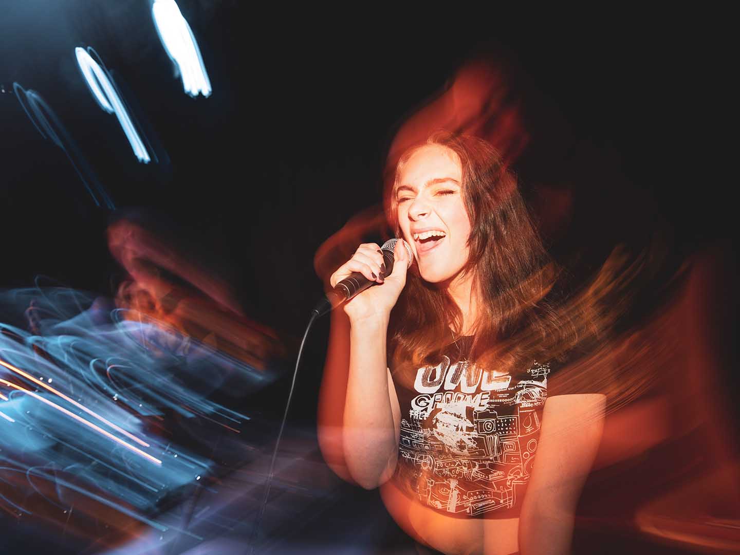 En elev blundar medan hon sjunger i en mikrofon under en konsert.