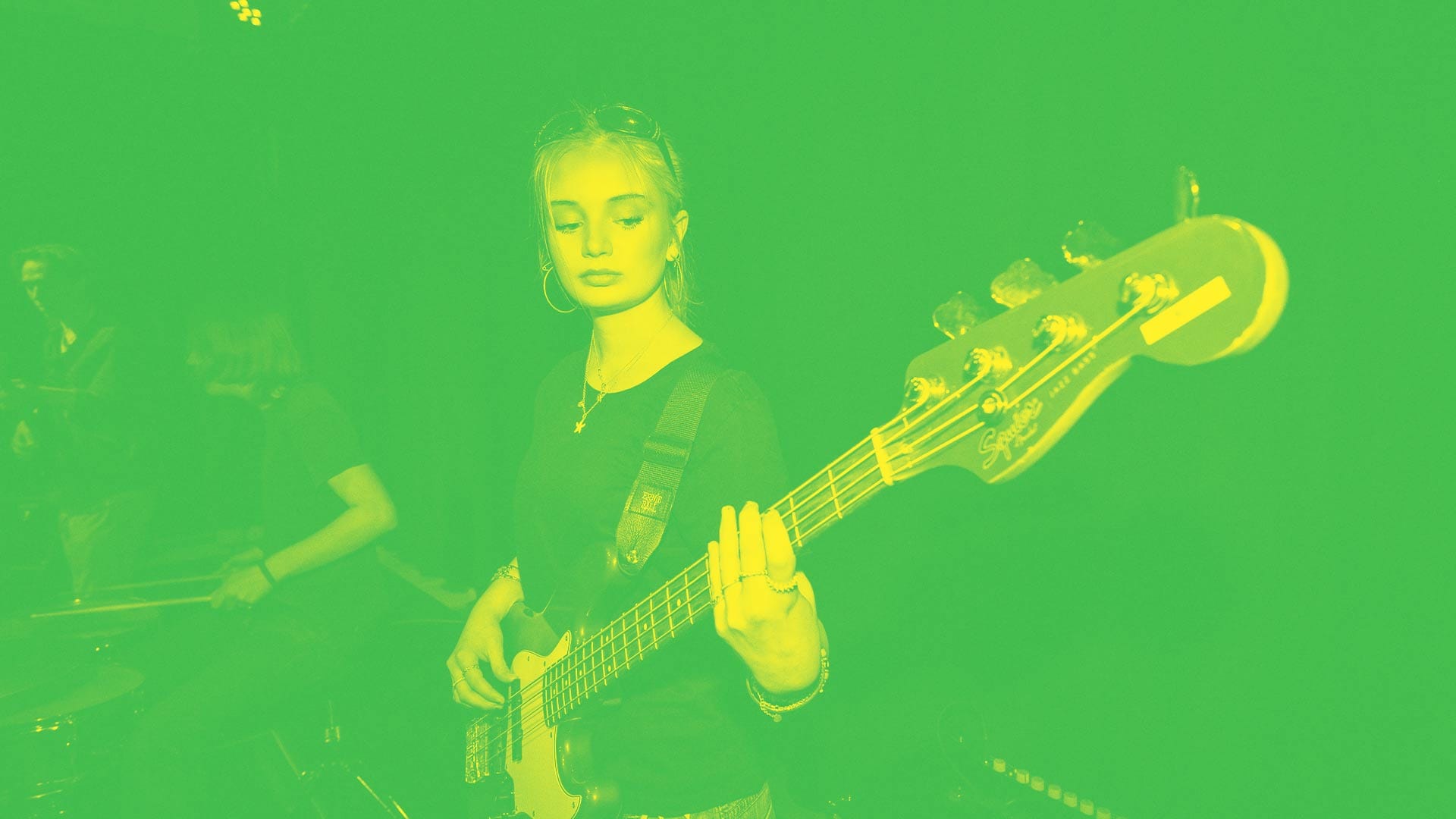 En elev spelar elbas på scen tillsammans med ett band.