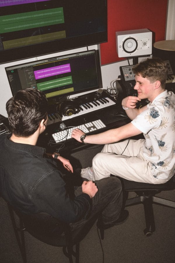 Två killar skapar musik ihop i musikstudion.