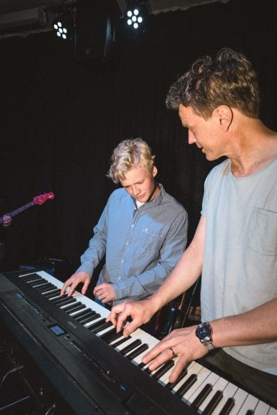 Lärare och elev spelar piano ihop.