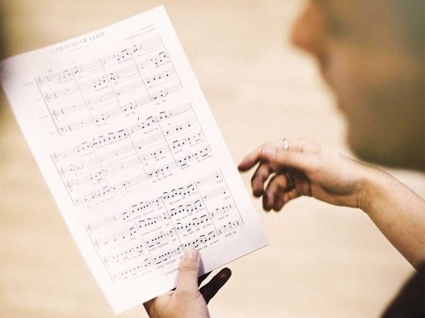 Två händer håller i ett notpapper med titeln Caravan of love.