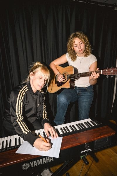 Elev spelar akustisk gitarr och lärare antecknar i notbladet.
