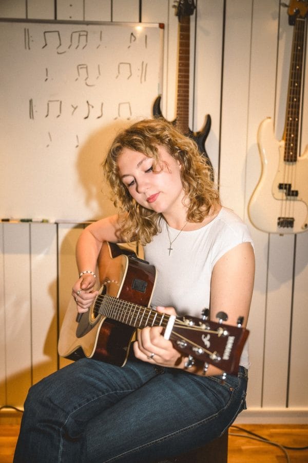 Tjej spelar på akustisk gitarr.