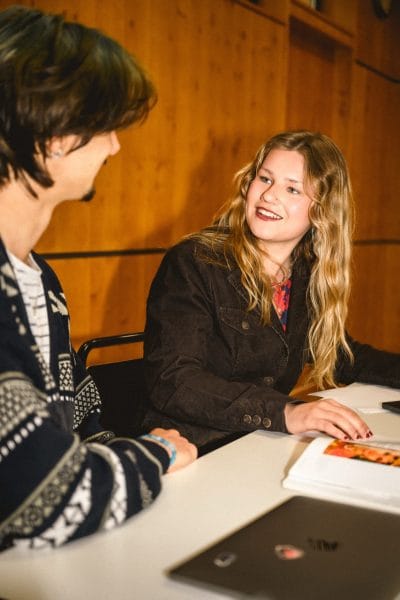 Två klasskompisar pratar med varann i klassrummet.